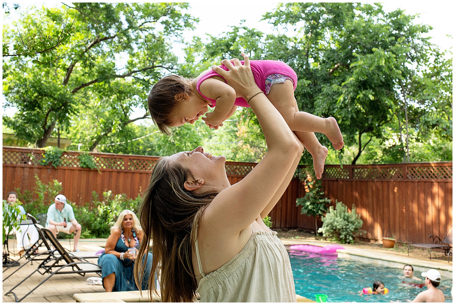 Mom holding baby up at first birthday party by the pool